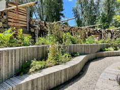 an outdoor garden with wood and plants on the sides, surrounded by stone retaining wall