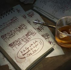 an open notebook with writing on it next to a glass of alcohol