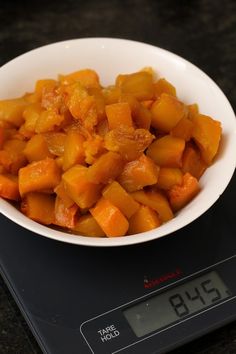 a white bowl filled with cut up carrots on top of a digital kitchen scale