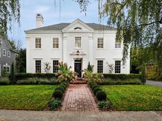 a large white house sitting on top of a lush green field