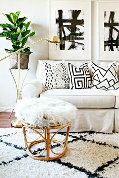 a living room with white couches and black and white artwork on the wall behind it