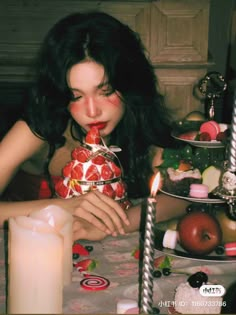 a woman sitting at a table in front of a cake with candles on top of it