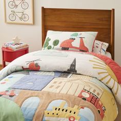 a child's bed with transportation themed comforter and pillow cases on the headboard