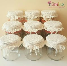 there are many jars with crocheted doily on top of each one,