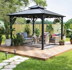 a gazebo sitting on top of a wooden deck next to a lush green field