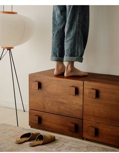 a person standing on top of a wooden dresser