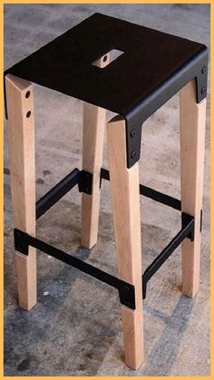 a small stool made out of wood and black leather with one foot on the seat