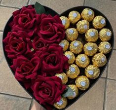 a heart - shaped box filled with chocolates and roses is shown in front of a person's hand