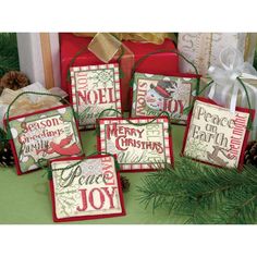 four christmas gift bags sitting on top of a table next to presents and pine cones