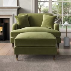 a green chair and ottoman in front of a window with a fire place behind it