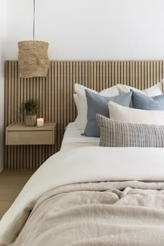 a bed with white sheets and pillows in a bedroom next to a wall mounted plant