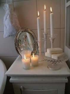 candles are lit in front of a mirror on a small table