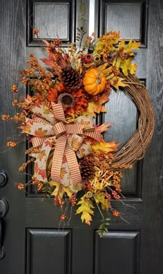 a wreath on the front door decorated with autumn leaves and pine cones