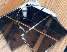 two mirrors sitting on top of a wooden table next to a brush and toothbrush