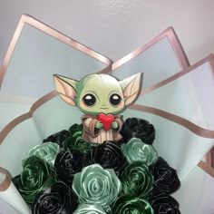 a star wars baby yoda holding a red heart surrounded by black rose bouquets