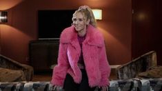 a woman wearing a pink fur coat in a living room