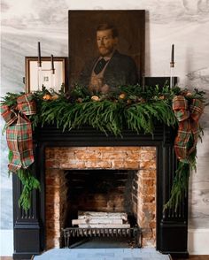 a mantel decorated with greenery and candles in front of a painting on the wall