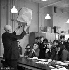 black and white photograph of a man holding something over his head in front of a group of people