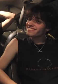 a young man sitting in the back seat of a car