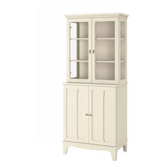 a white china cabinet with glass doors on the top and bottom shelves, in front of a white background