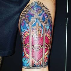 a man's arm with a stained glass window and cross tattoo on the sleeve