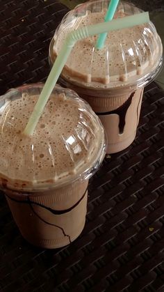 two plastic cups with straws in them sitting on a table