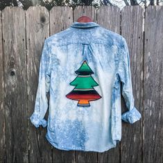 a tie dye shirt with a christmas tree on the front and back, hanging on a wooden fence