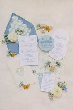 the wedding stationery is laid out on top of the table with flowers and butterfly brooches