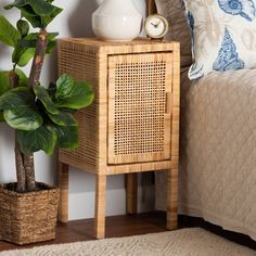 a wicker side table with a clock on it next to a potted plant