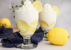 two glasses filled with lemonade and whipped cream next to some lemons on a table