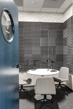 an office cubicle with two chairs and a round table in front of the wall