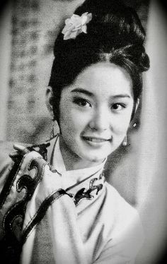 an old photo of a woman in traditional dress smiling at the camera with her hair pulled back