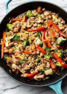 a skillet filled with stir fry vegetables and meat