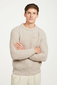 a man in a sweater is posing with his arms crossed