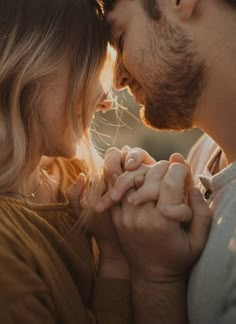 a man and woman are holding hands while looking at each other's foreheads