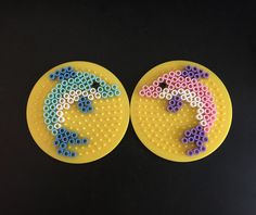 two yellow plates with different colored beads on them, one is shaped like a horse