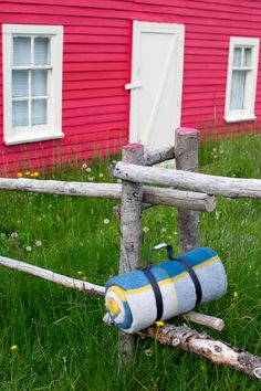 an old wooden fence with a rolled up tube on it in front of a red house