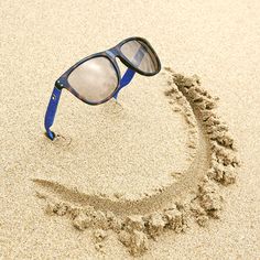 a pair of glasses sitting on top of a sandy beach