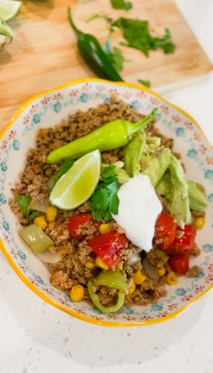 a bowl filled with rice and vegetables on top of a wooden cutting board