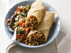 two burritos on a blue plate with a spoon