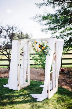 an outdoor ceremony setup with white drapes and flowers