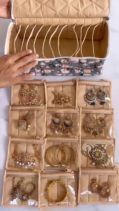 an open box with many different types of jewelry in it and someone holding the lid