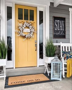 a yellow front door with a welcome mat on the ground and two chairs in front