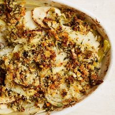 a casserole dish with broccoli and other toppings in it on a white surface