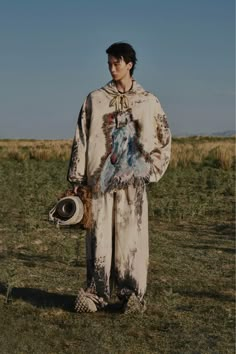 a man standing in the middle of a field holding a hat and a baseball mitt