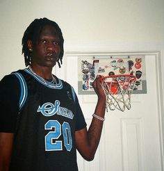 a young man holding a basketball in front of a wall hanging on a white door