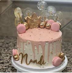 a pink and white cake with gold decorations on top that says naddi in large letters