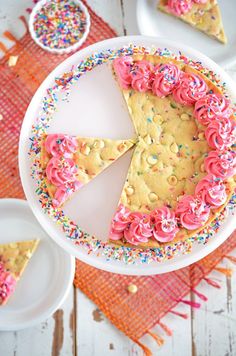 a cake with pink frosting and sprinkles sits on a white plate