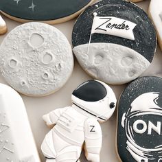 cookies decorated to look like astronauts and astronauts on the moon, with one cookie in the shape of an astronaut's helmet