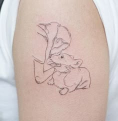 a woman with a small tattoo on her arm is holding a baby kangaroo in her lap